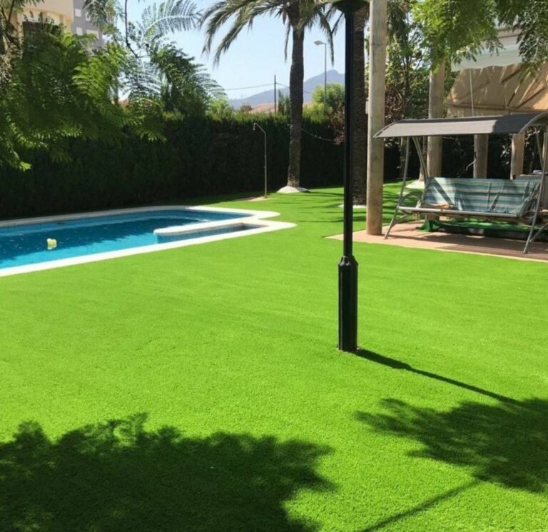 Jardín con césped artificial, palmeras y piscina en Canarias